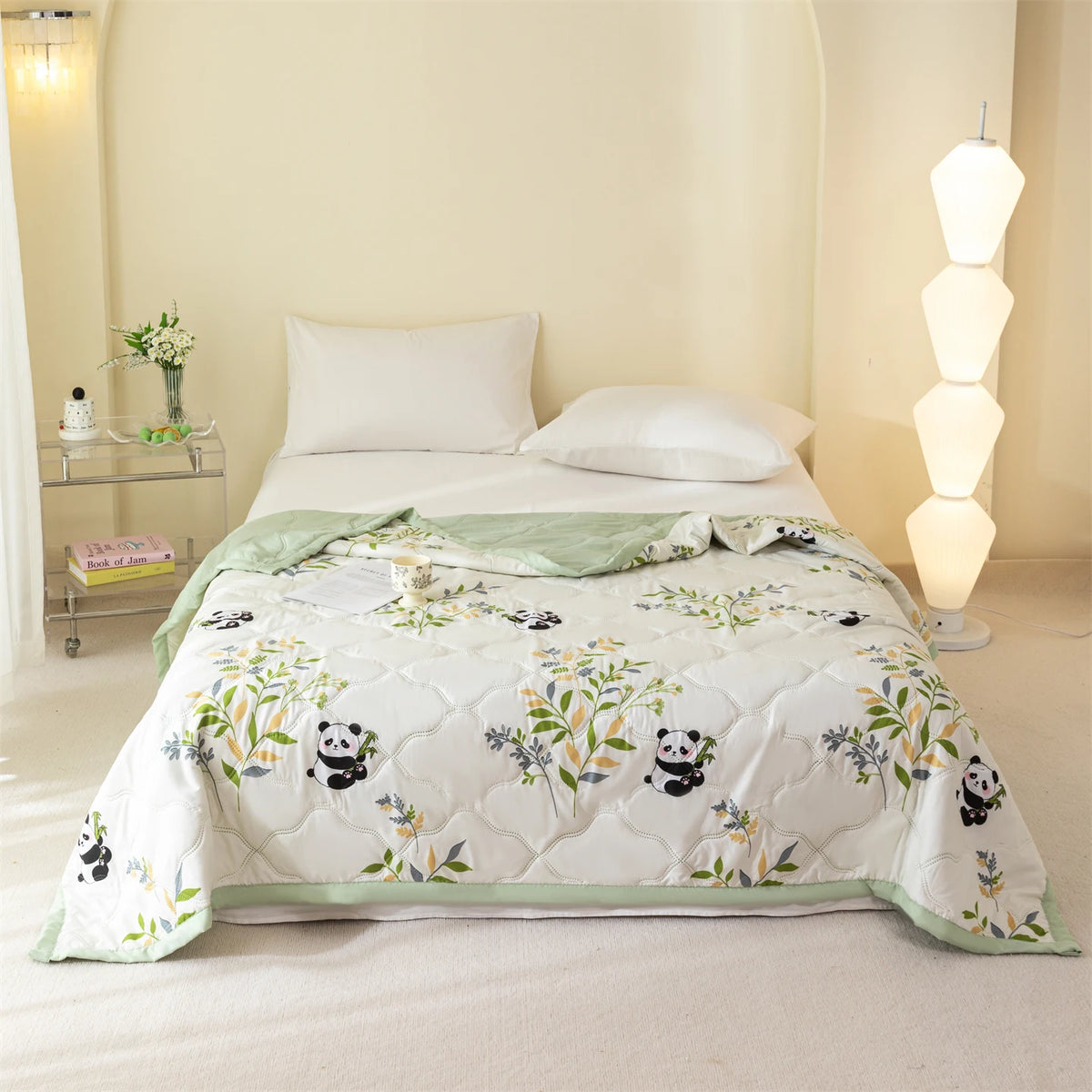 A white quilted bedspread featuring a floral pattern and black panda designs on a light-colored bed.