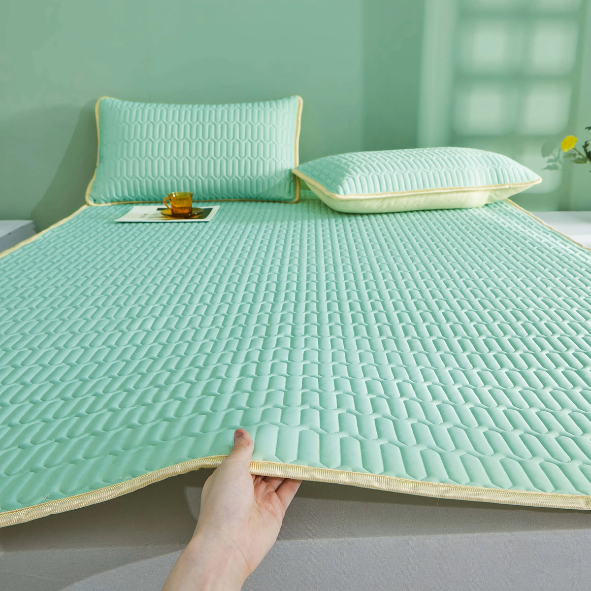 Almohadilla de colchón transpirable de color verde menta claro con textura acolchada y una almohada a juego en una cama.