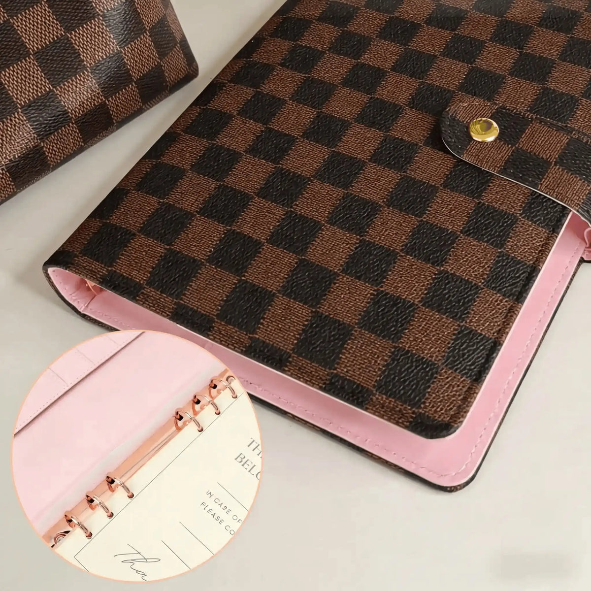 A brown checkered PU leather portfolio with a pink lining and gold hardware.