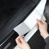 A hand is applying a carbon fiber door sill protector sticker to the side of a car door.