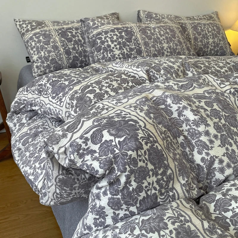 A close-up of a gray and white floral printed duvet cover set with pillows on a bed.