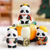 A blind box panda figure wearing an orange cape and a gold crown standing on a white snowy surface.