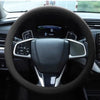 Close-up view of a black steering wheel with an anti-slip silicone cover and controls inside a car interior.