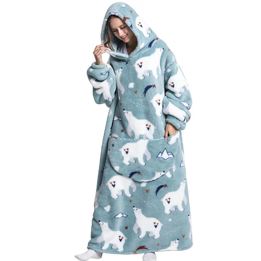 A woman wearing a light blue oversized wearable blanket hoodie with a hood and sleeves.