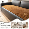 A brown quilted plush sofa cover with a non-slip mat is shown on a dark leather sofa.
