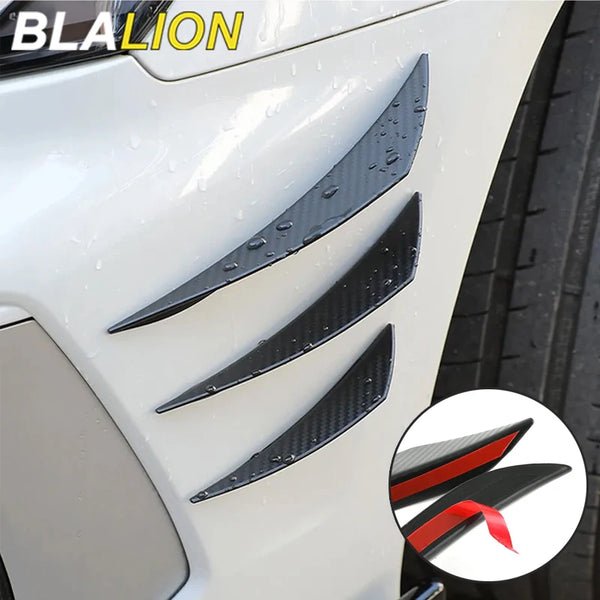 A close-up of a white car featuring a black, carbon fiber style front bumper lip splitter set.