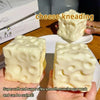 A close-up of a white cheese kneading squishy toy being squeezed by hands.