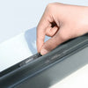 A hand is applying a self-adhesive window screen repair patch to the edge of a window frame.