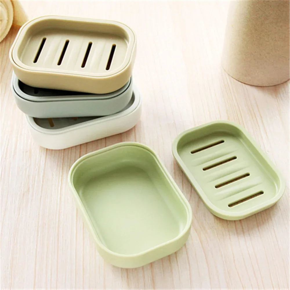A set of light green and beige compact travel soap holders with secure lids arranged on a wooden surface.