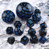 A collection of 15 polyhedral dice in various sizes and colors scattered on a white surface.