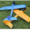 Two foam glider planes, one blue and one orange, resting on green grass.