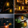 A set of glass lanterns with flickering yellow light hanging outdoors at night.