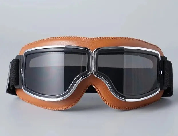 A pair of brown leather retro foldable motorcycle goggles with black lenses and silver trim.