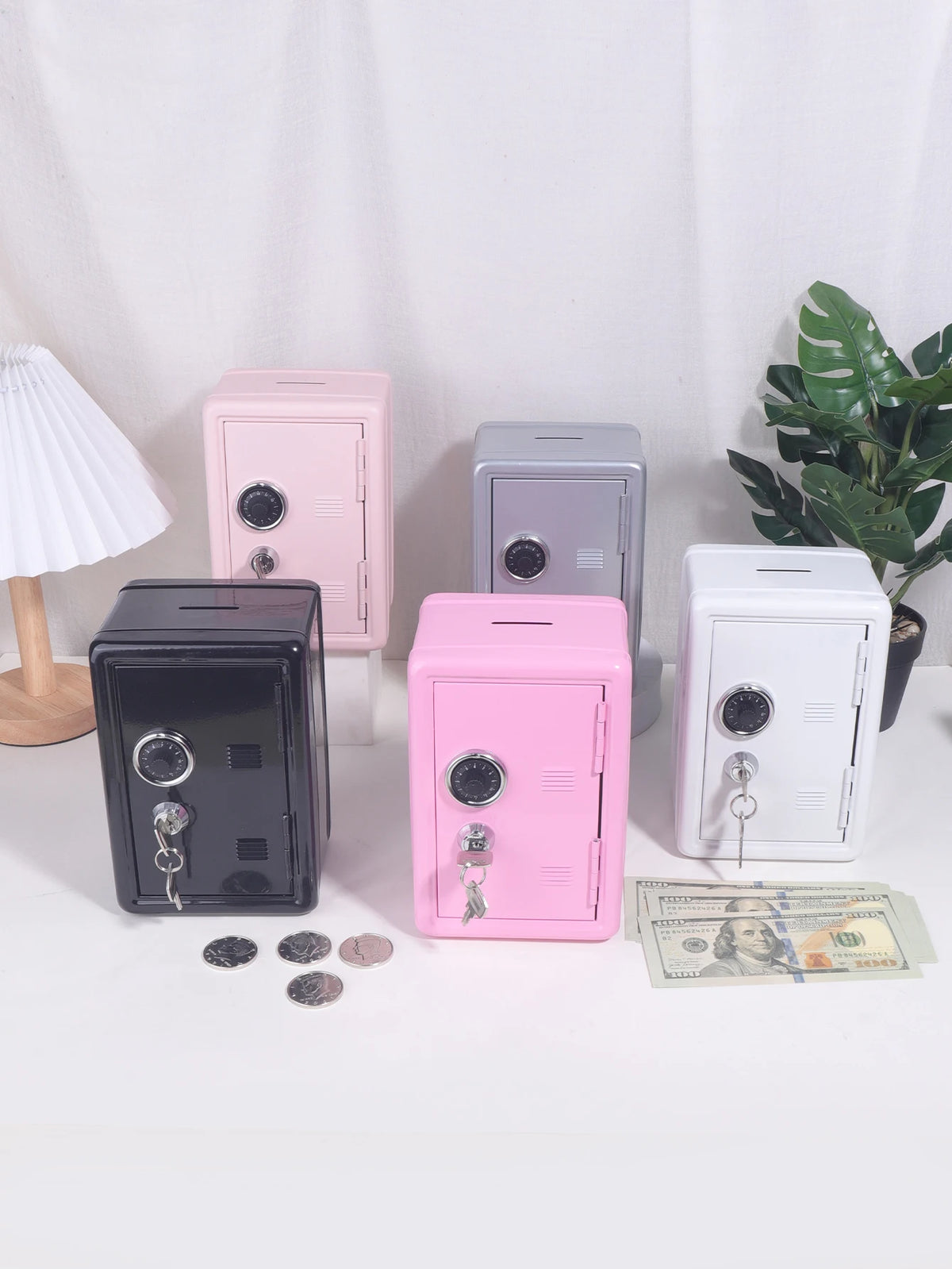A collection of vintage metal piggy banks in pink, gray, and black, displayed on a white surface with some US currency.