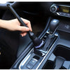 A hand is using a soft bristle interior detailing brush to clean the gear shift of a car.