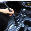 A hand is using a soft bristle interior detailing brush to clean the gear shift and console of a car.