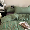 A green and white striped duvet cover set with matching pillowcases on a bed.