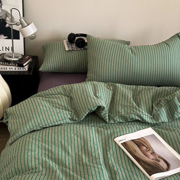 A green and white striped duvet cover set with matching pillowcases on a bed.