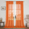 Orange sheer curtains with a floral pattern hanging in a glass door frame.