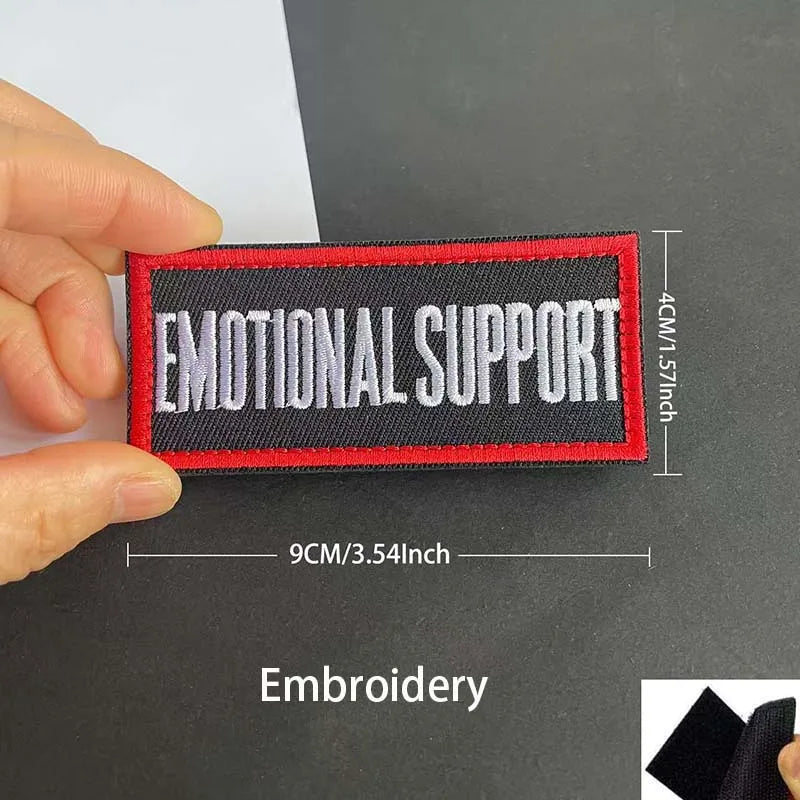 A close-up of a red embroidered patch with the text EMOTIONAL SUPPORT on a black background.