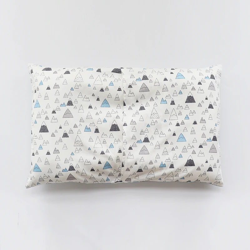 A white baby pillowcase featuring a pattern of gray and blue mountain shapes.