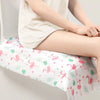 A person is sitting on a white disposable toilet seat cover decorated with pink and green flamingo patterns.