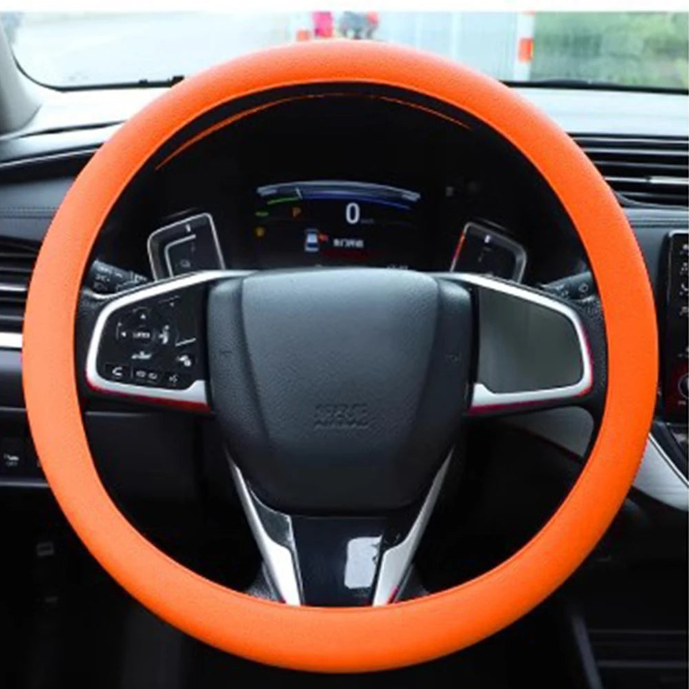 Orange silicone steering wheel cover on a car's interior dashboard.