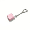 A pink, square mechanical keyboard fidget keychain with a silver chain and clasp.