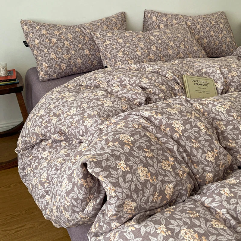 A set of soft printed duvet covers and pillowcases in a muted taupe color with a floral pattern.