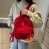 A person is wearing a red corduroy casual backpack over a cream sweater.