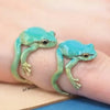 A small, bright turquoise green tree frog ring worn on a finger.