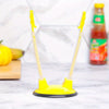 A yellow adjustable bag holder rack with long plastic arms is displayed on a white marble surface.