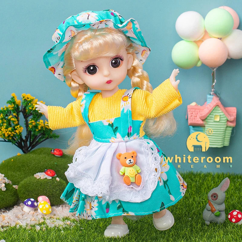 A blonde fashion doll dressed in a yellow top and teal skirt with floral details, standing in a grassy outdoor setting.