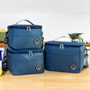 A navy blue insulated lunch bag with a shoulder strap is shown on a wooden surface.