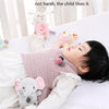 A baby is lying down and enjoying a soft plush rattle toy with a cartoon elephant design.