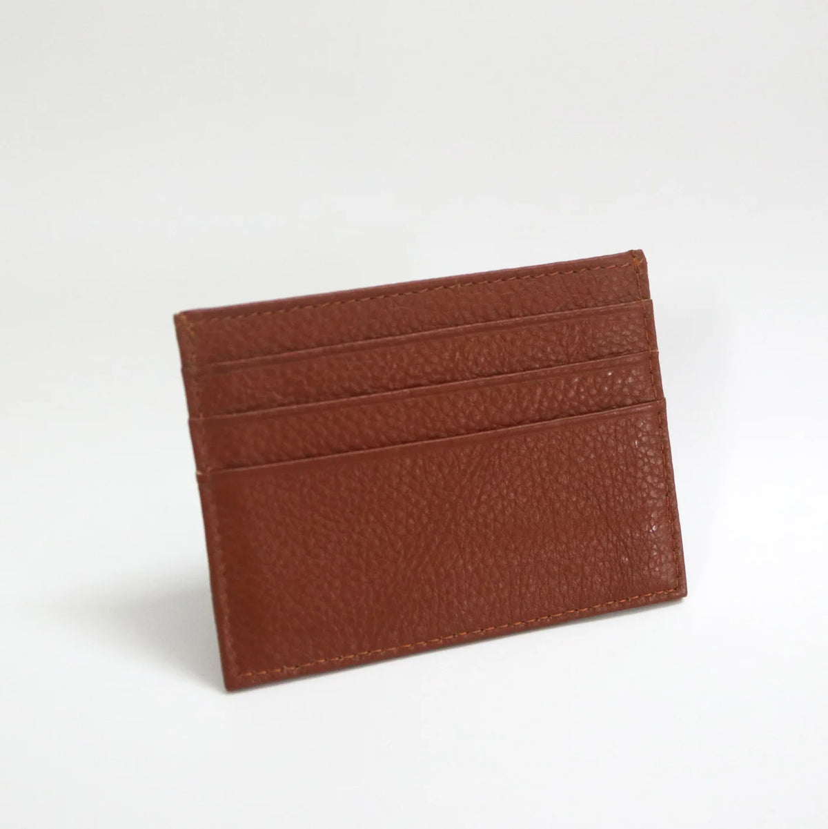 Porta tarjetas de cuero genuino marrón y delgado con múltiples ranuras horizontales.