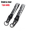 A black leather lanyard with white text is shown, featuring a metal clasp for a keychain.