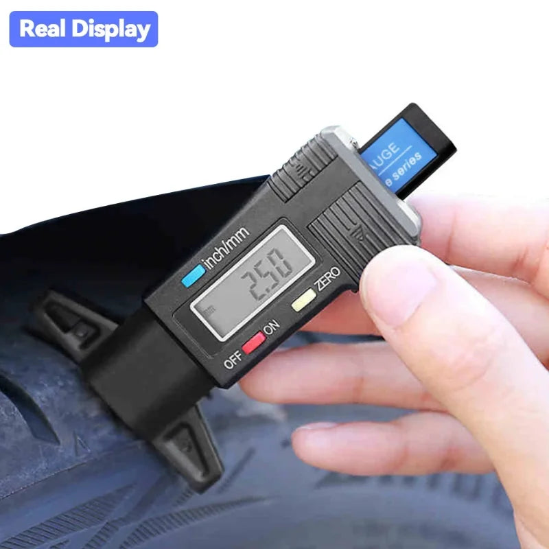 A hand holds a black digital tire tread depth gauge with a display showing 2.50 inch and an ON/OFF switch.
