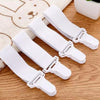 A set of four white adjustable bed sheet holder clips lying on a wooden surface.