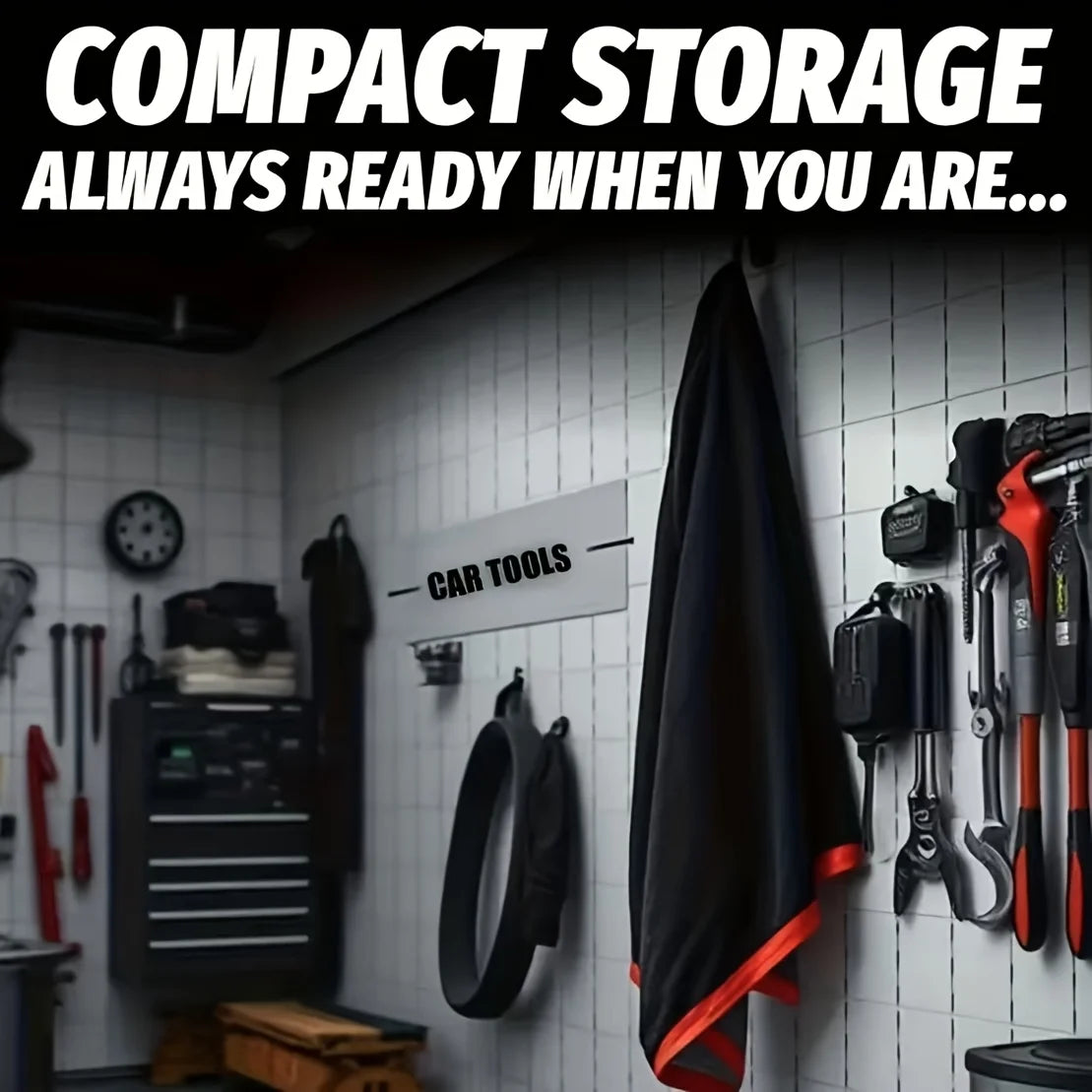 A black microfiber car drying towel is hanging on a white tiled wall next to various car tools.