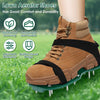 A close-up of brown lawn aerator shoes with black straps and metal spikes resting on green grass.