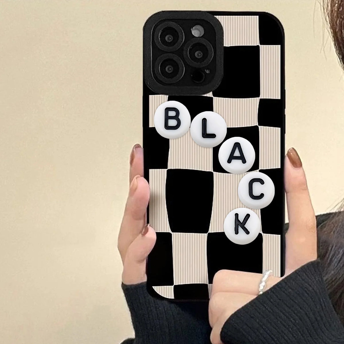 A close-up photo of a smartphone displaying black and white checkered pattern with individual letters B L A C K arranged in w