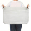 A person holds a white woven cotton rope storage basket with handles.