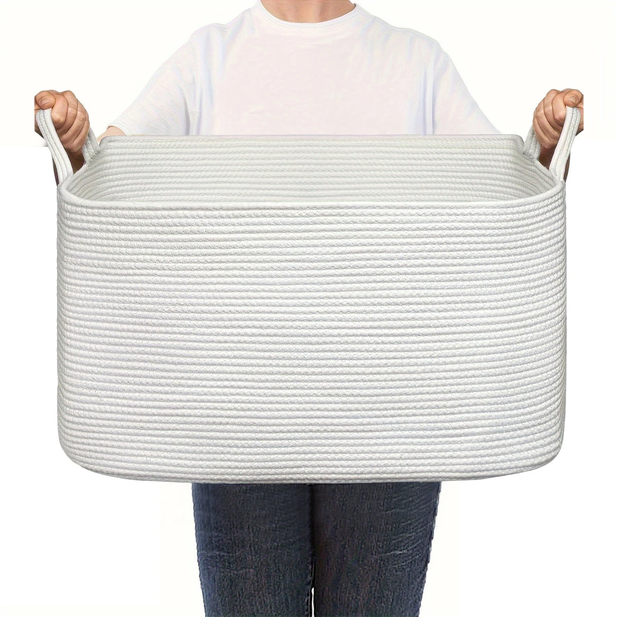 A person holds a white woven cotton rope storage basket with handles.