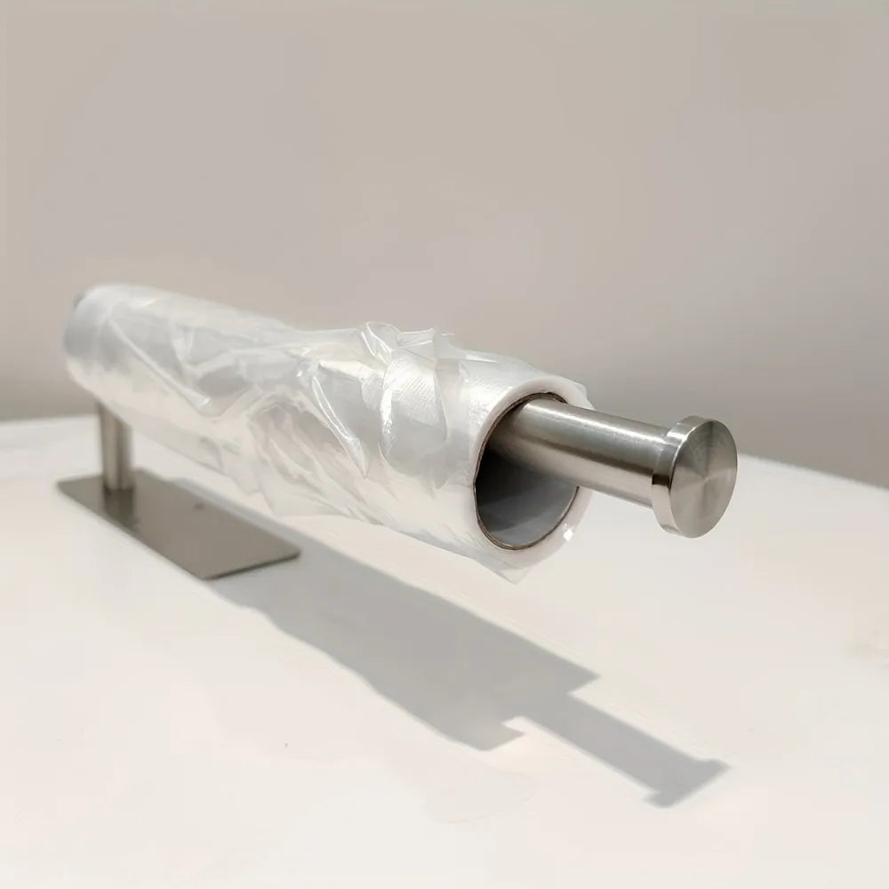 A stainless steel under-cabinet paper towel holder wrapped in clear plastic film.
