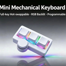 A white mini mechanical keyboard with RGB backlight and a round knob is shown on a reflective surface.