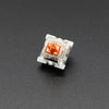 A close-up view of an Outemu mechanical keyboard switch, featuring a white housing and an orange-colored stem.