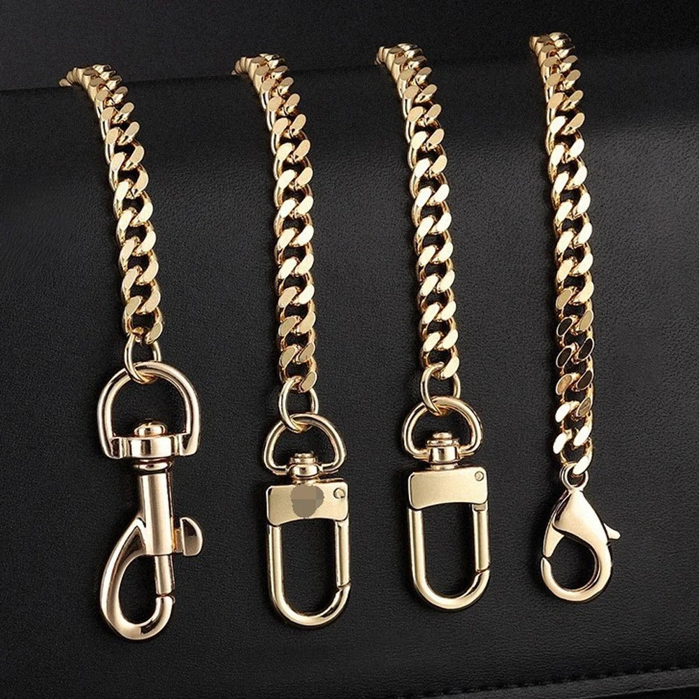 Four gold-colored metal purse chains with buckles displayed on a dark surface.