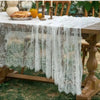 Elegant white lace tablecloth with French retro floral design draped over a wooden table.