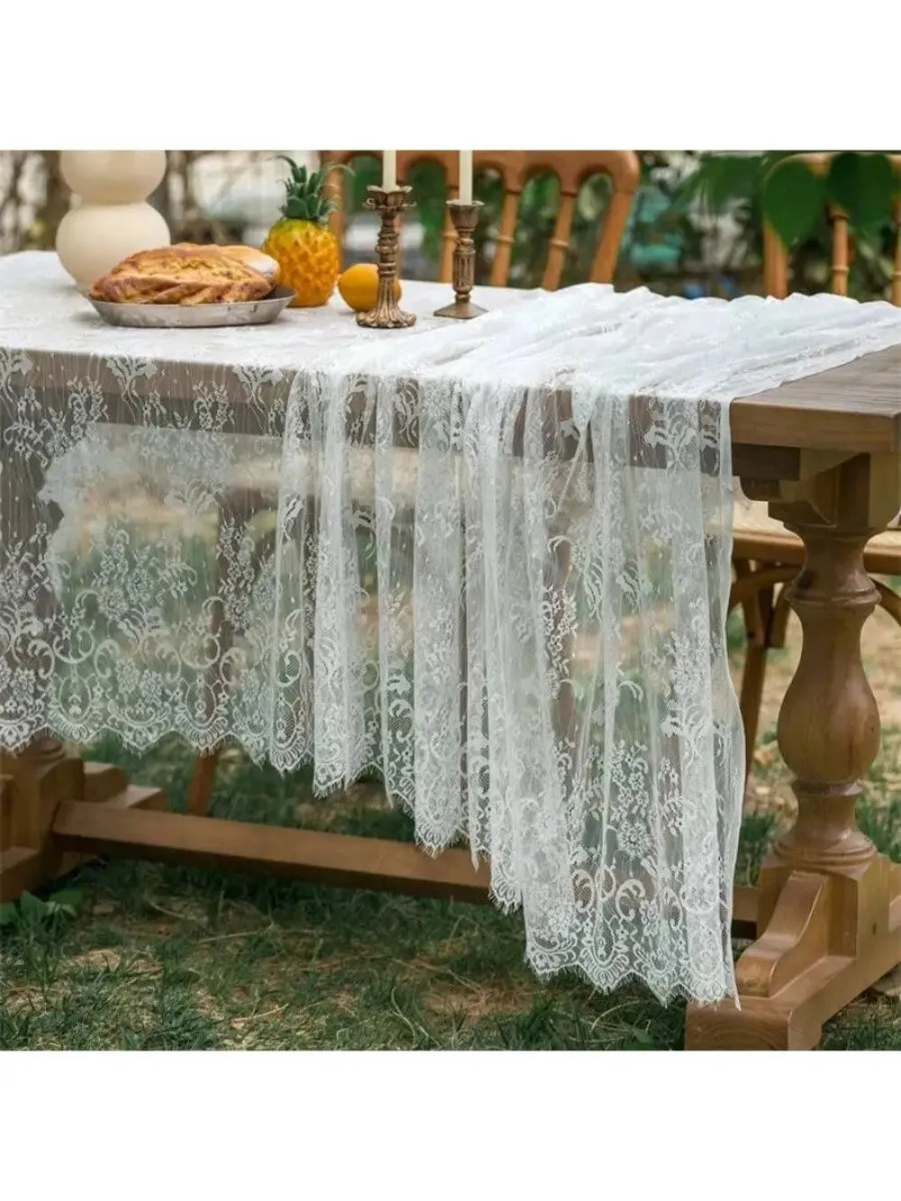 Elegant white lace tablecloth with French retro floral design draped over a wooden table.